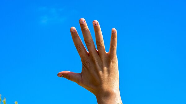Picture of a raised hand with a blue sky in the background.